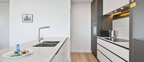 Una cocina moderna con un lavamanos de acero inoxidable, una cafetera y un refrigerador.