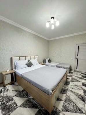 A bedroom with a large bed, two bedside tables, a nightstand, and a ceiling light fixture.
