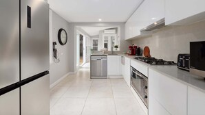 Una cocina moderna con armarios blancos, electrodomésticos de acero inoxidable y un diseño limpio y minimalista.