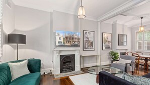 Una sala de estar con chimenea, sofá verde y una mesa de centro de vidrio.
