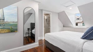 Un dormitorio moderno con una cama grande, un espejo y un cuadro de un paisaje.
