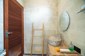 A bathroom with a wooden door, a wooden ladder, a stone sink, a mirror, and a soap dispenser. - Armonia Private Villa Ubud (Ubud)