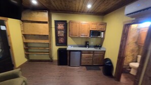 A compact kitchen with wooden cabinets, a microwave, and a small refrigerator.
