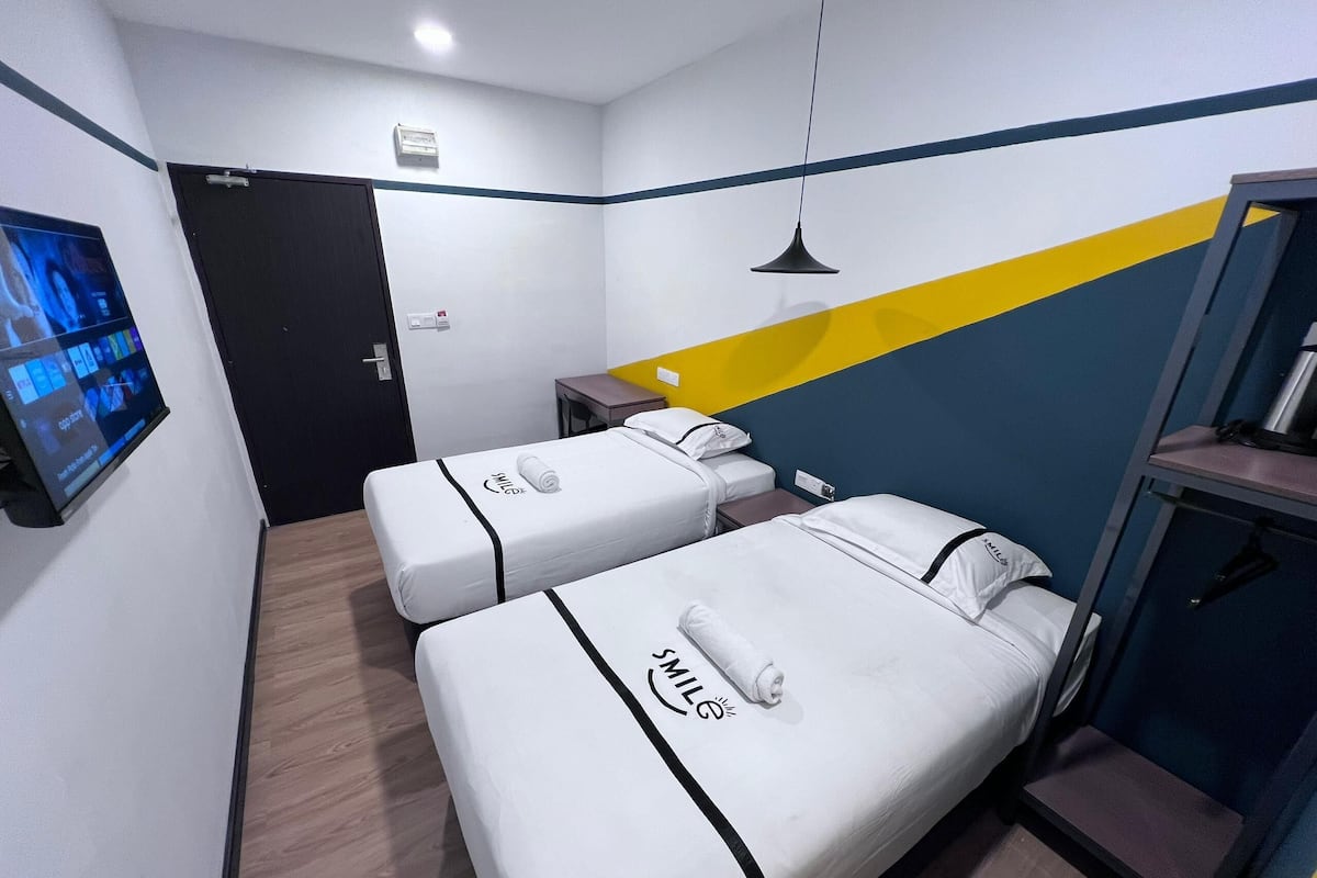 A hotel room with two beds, a TV, a desk, and a small table.