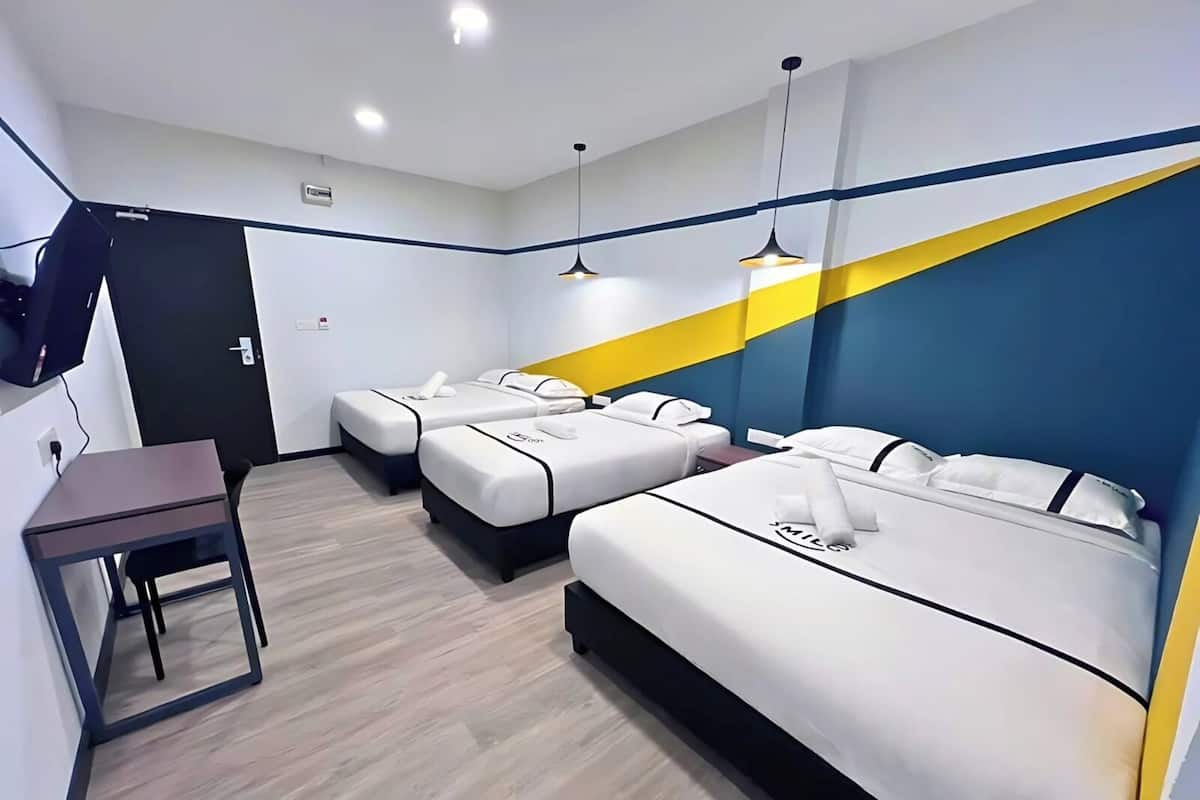 A hotel room with a bed, a desk, and a TV mounted on the wall.