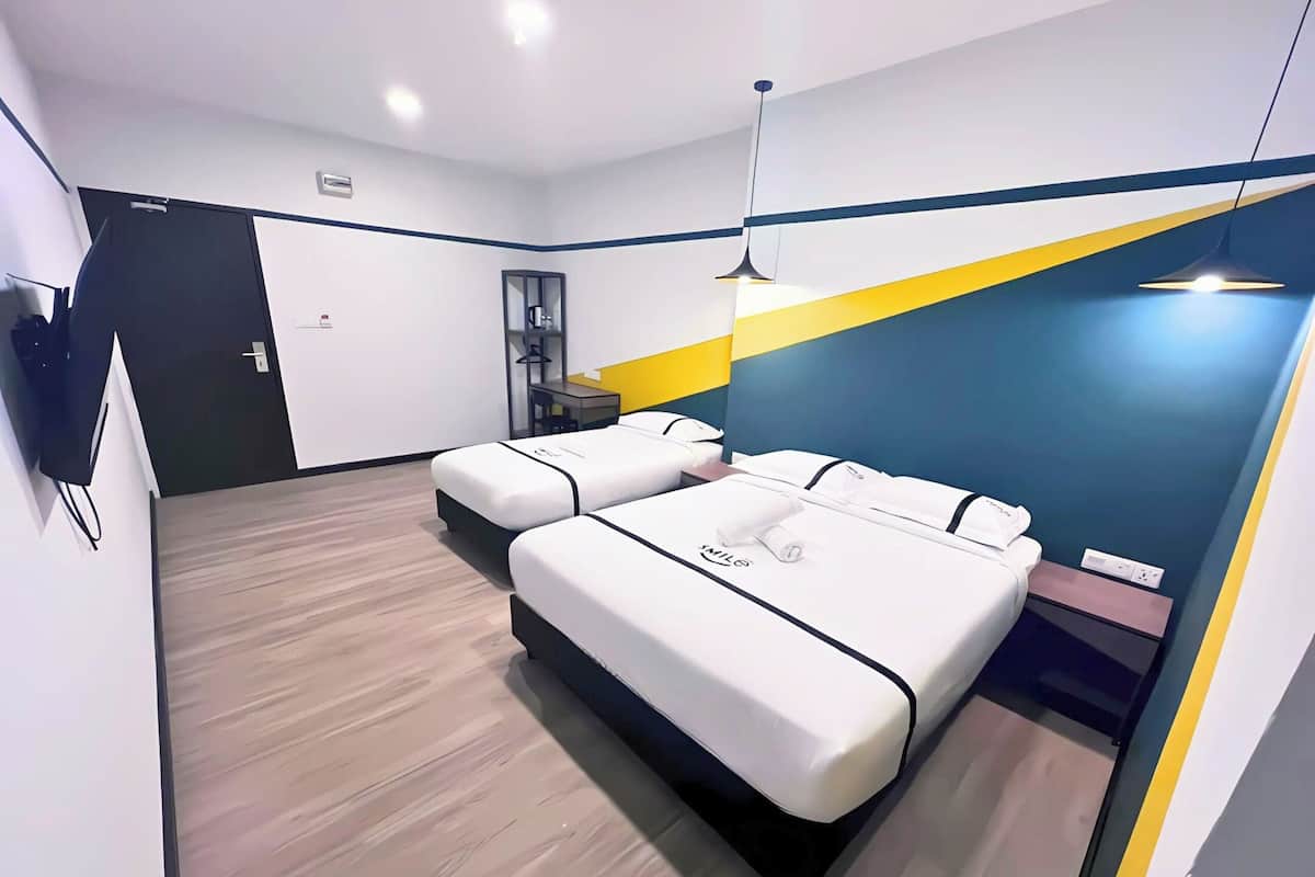 A modern hotel room with two beds, a desk, and a mirror.