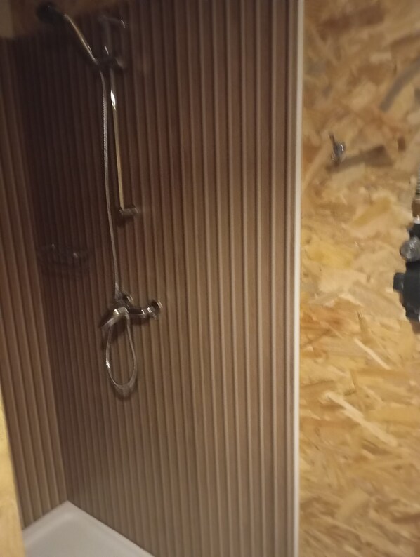 Un baño con ducha, toallero y pared de madera con textura.