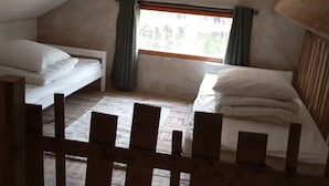 A small, dimly lit attic room with two beds and a window.