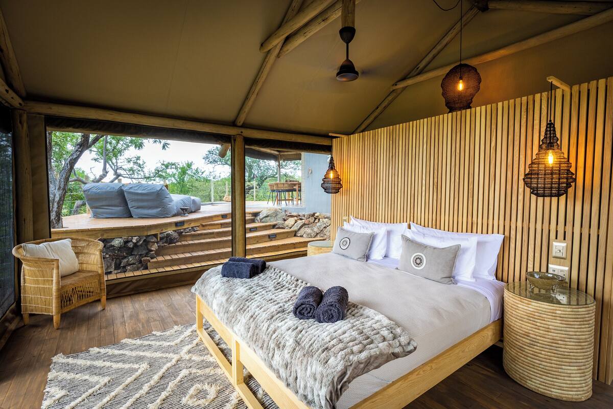 A bedroom with a large bed, wooden headboard, and a view of the outdoors.