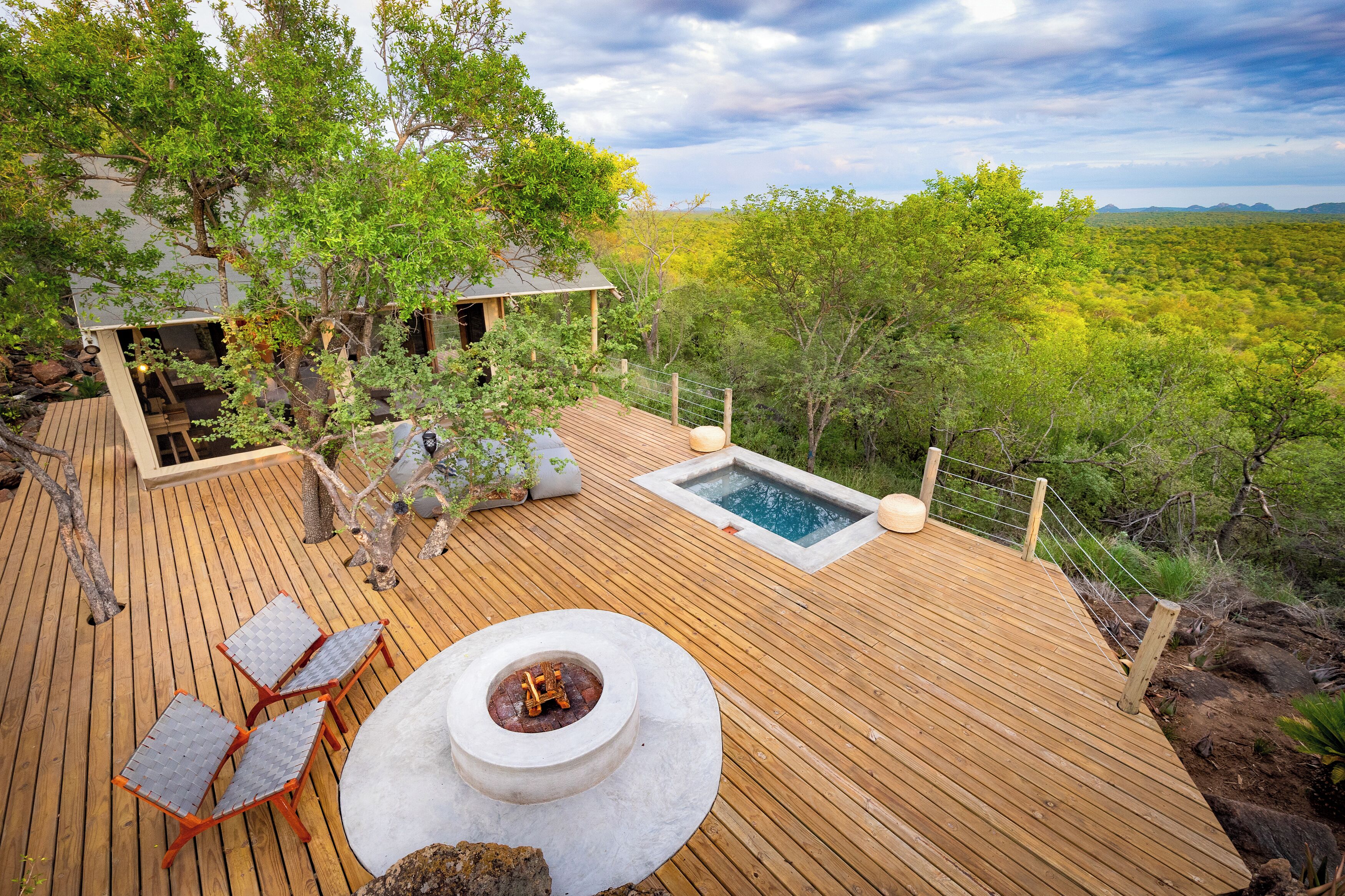 A wooden deck with a fire pit, outdoor seating, and a hot tub.