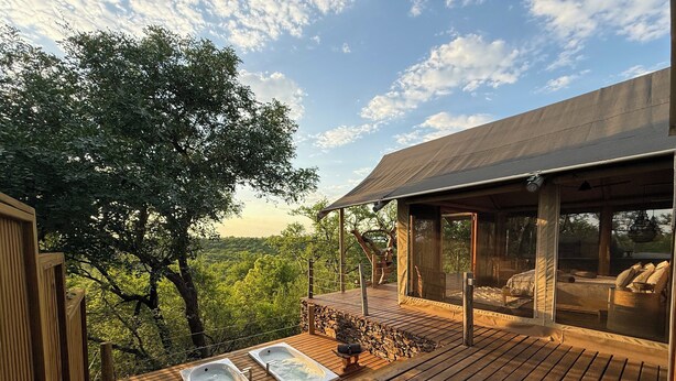 A wooden deck with two hot tubs, a covered seating area, and a view of a forested landscape. - Bushveld Bivouac Private Camp (Mica)