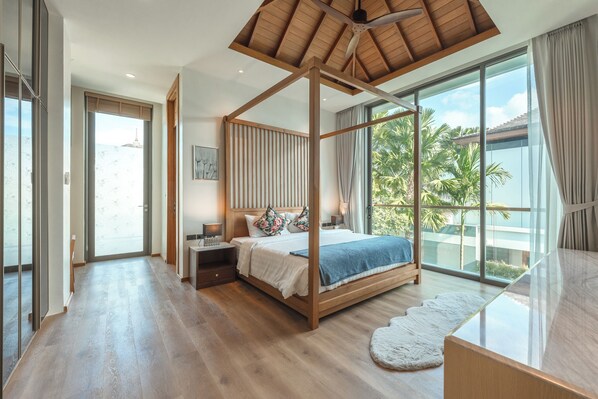 A spacious bedroom with a four-poster bed, large windows, and a view of palm trees. - Near Best Beaches Boat Avenue V218 (Choeng Thale)
