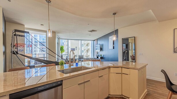 A modern kitchen with a dishwasher, wooden cabinets, and a large island.