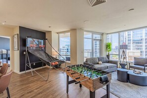 A modern living room with a foosball table, a basketball hoop, and a sofa.