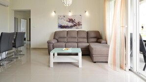 Un salon moderne avec un canapé d’angle, une table basse en verre et une suspension contemporaine.