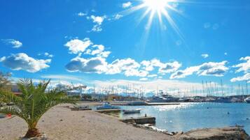 A beach with a clear sky, palm trees, and boats.