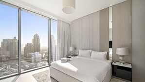 A modern hotel room with a large bed, two bedside tables, and a city view.