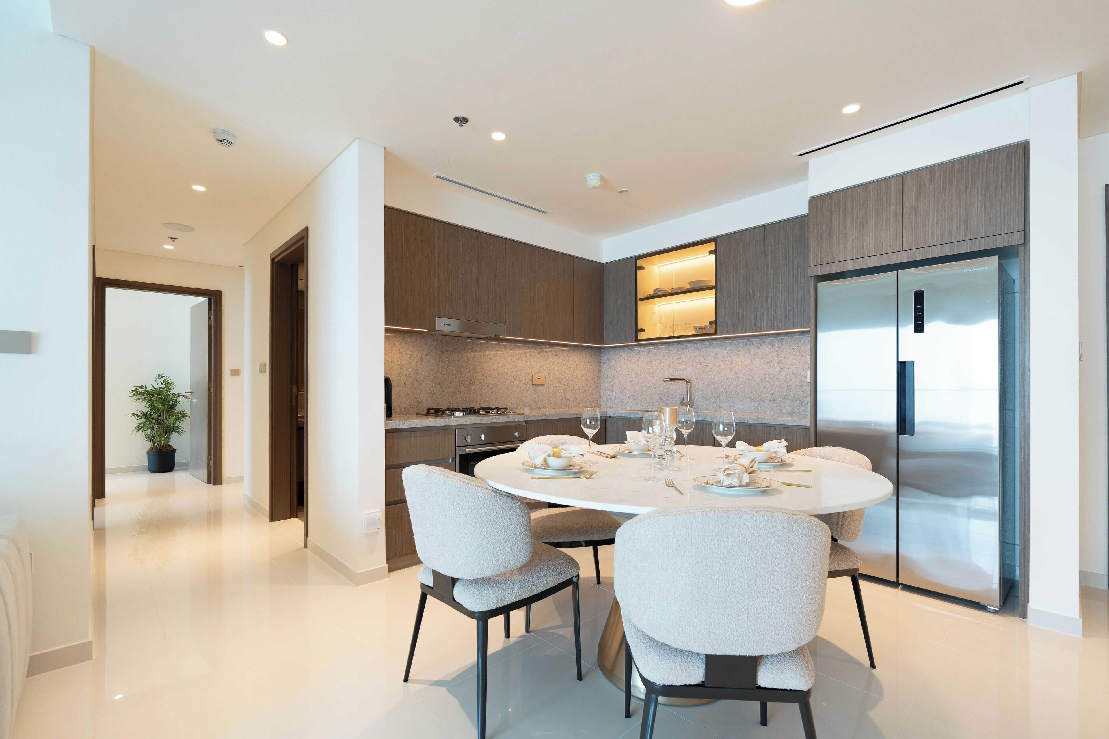 Una cocina moderna con una mesa redonda de comedor, electrodomésticos integrados y una planta en maceta.