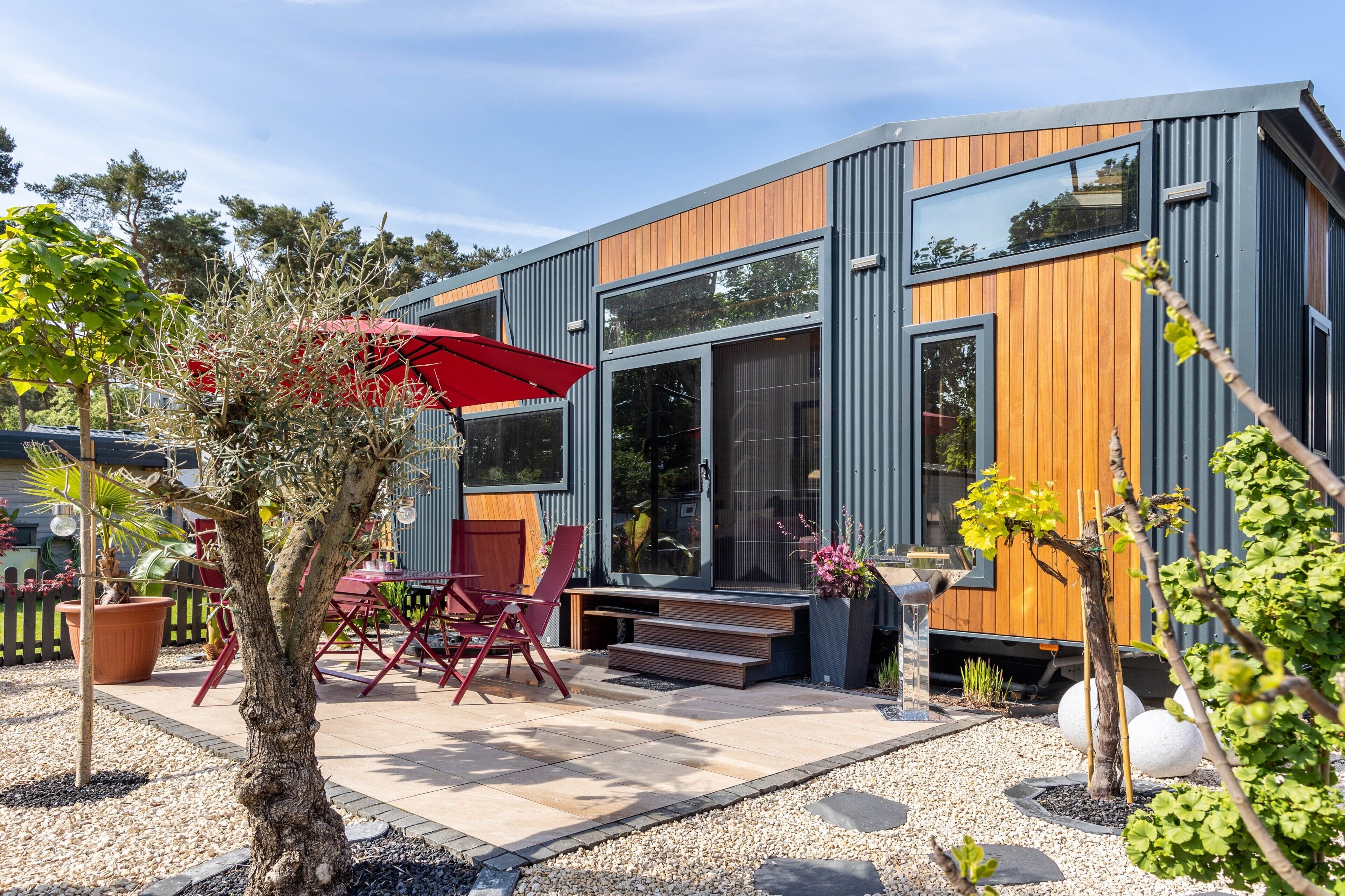 Una casa moderna con patio, mobili da esterno e giardino.