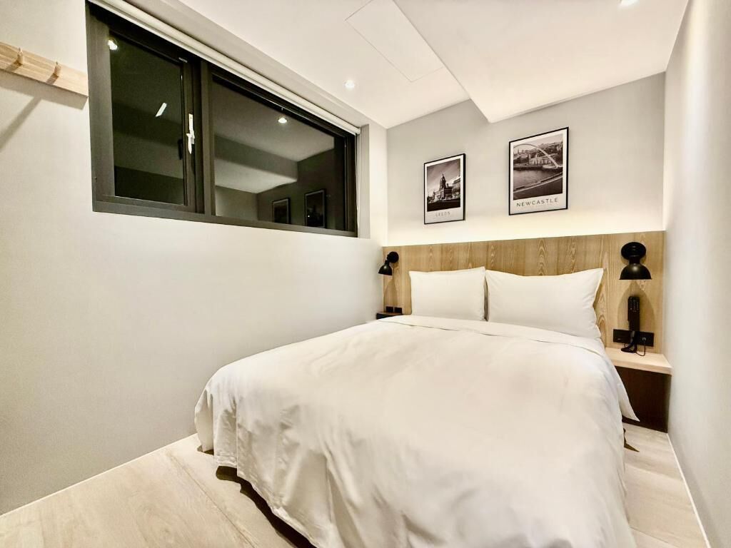 A modern bedroom with a large bed, a window, and two framed pictures on the wall.