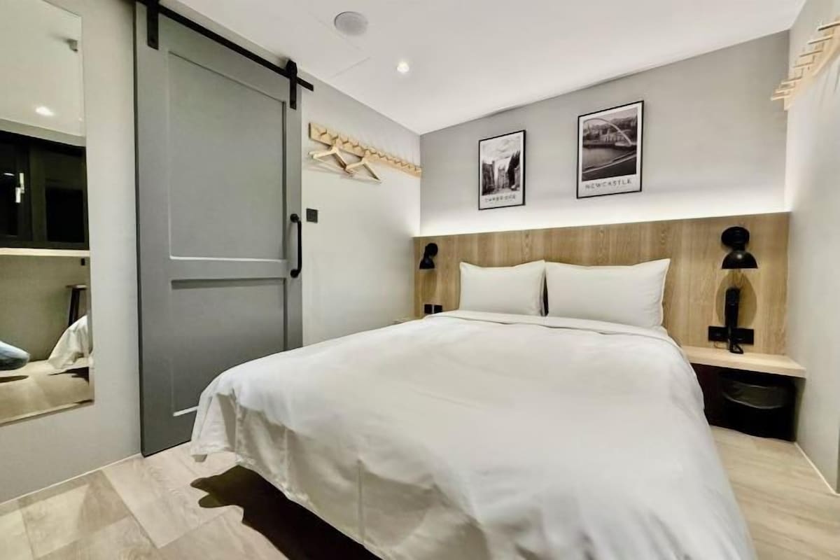 A modern bedroom with a large bed, a wardrobe, and two framed pictures on the wall.