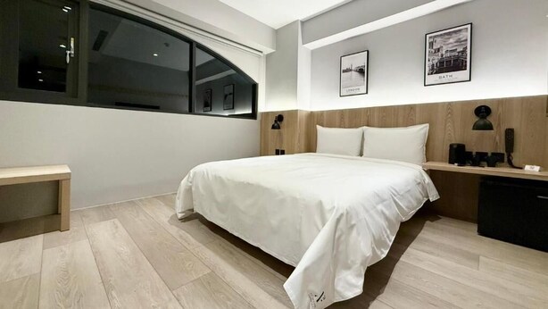 Un dormitorio moderno con una cama grande, una mesita de noche y una ventana.