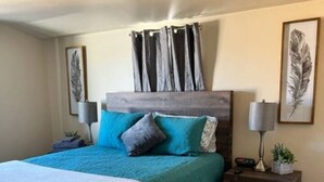 A bedroom with a bed, a nightstand, a lamp, and a wall-mounted shelf. - Modern New Mexico Loft in the heart of Las Cruces. (Las Cruces)