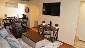 A living room with a sofa, armchair, coffee table, and a TV mounted on the wall. - Modern New Mexico Loft in the heart of Las Cruces. (Las Cruces)