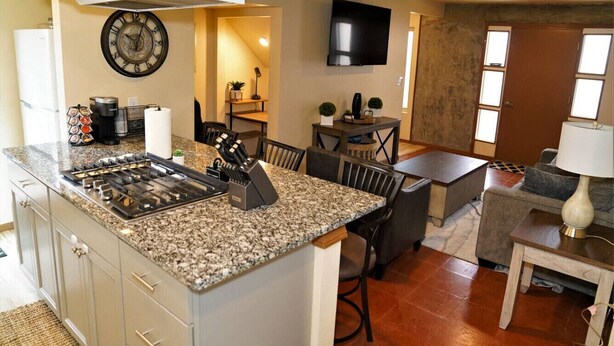 A kitchen with granite countertops, a stove, and a dining area with a table and chairs. - Modern New Mexico Loft in the heart of Las Cruces. (Las Cruces)