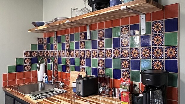 Eine Küche mit einer Holz Arbeitsplatte, einem Edelstahl-Spülbecken, einer Mikrowelle und einer Kaffeemaschine.
