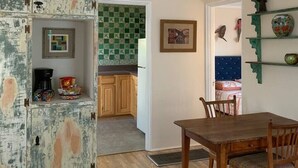 A dining area with a wooden table and chairs, a kitchen with green patterned tiles, and a rustic cabinet with shelves. - 2 bed and pullout sofa kids and dogs welcome (Las Cruces)