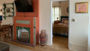 A living room with a fireplace, a television mounted above it, and a bed in the adjacent room. - 2 bed and pullout sofa kids and dogs welcome (Las Cruces)
