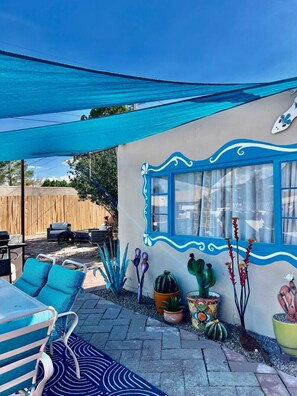 A patio area with outdoor furniture, a blue awning, and decorative plants. - Mid-century marvelous 1 bed, pets welcome! (Las Cruces)