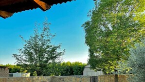 Un espace extérieur rustique agrémenté d’un grand pot en argile, d’un mur en pierre et d’une structure couverte.