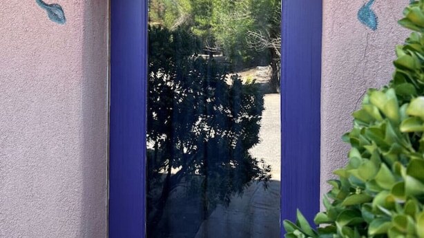 Une porte dotée d’un cadre violet et ornée d’un motif floral décoratif au-dessus.