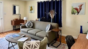 Una sala de estar con sofá, sillones, una mesa de centro, una mesa de comedor y un ventilador de techo.