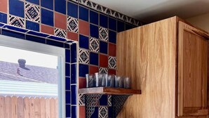 Una cocina con encimera de madera, un fregadero, una ventana y un salpicadero con baldosas azules y rojas.
