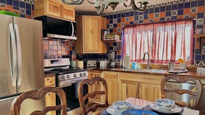 Una cocina con armarios de madera, un refrigerador, una estufa y una mesa de comedor con platos azules y blancos.