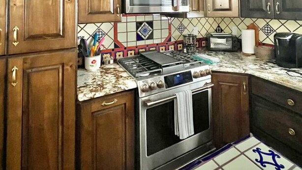 A kitchen with wooden cabinets, a microwave, a stove, and a tiled backsplash. - 2 king bds/2.5 bathrooms in the heart of Downtown (Las Cruces)