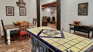 A dining area with a tiled table, wooden chairs, and a hanging light fixture. - 2 king bds/2.5 bathrooms in the heart of Downtown (Las Cruces)