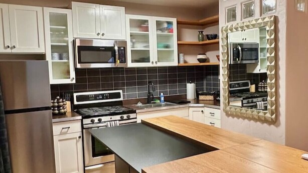 A modern kitchen with white cabinets, a central island, and a microwave above the sink.