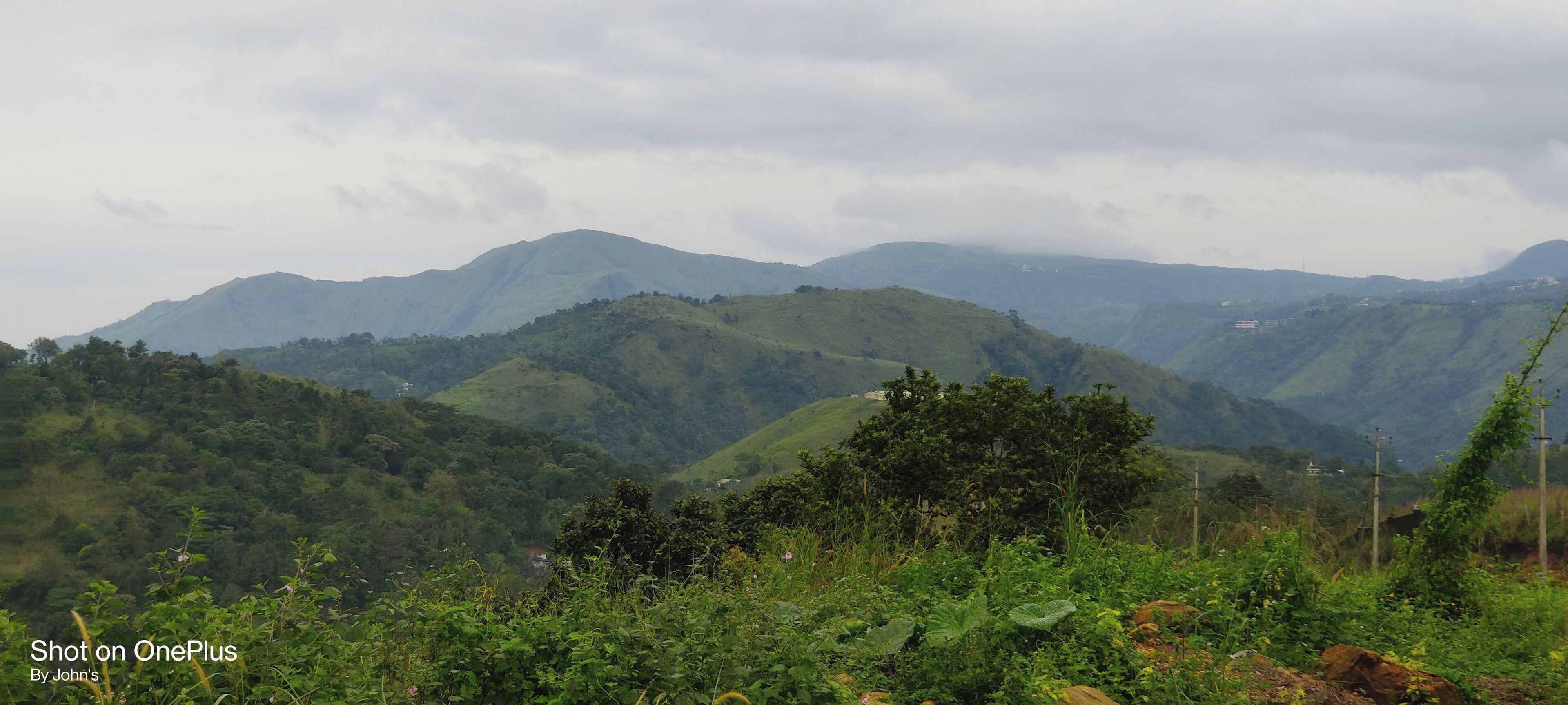Un paisaje montañoso con abundante vegetación y colinas al fondo.
