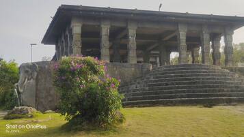 A large stone structure with a roof supported by columns, a staircase leading up to it, and a statue of an elephant.