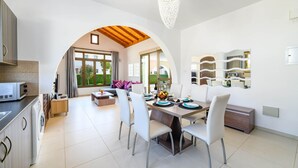 A modern kitchen with a dining area, featuring a large table, chairs, and a chandelier.