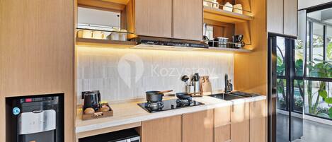A modern kitchen with built-in appliances, wooden cabinetry, and a large window offering a view of greenery.