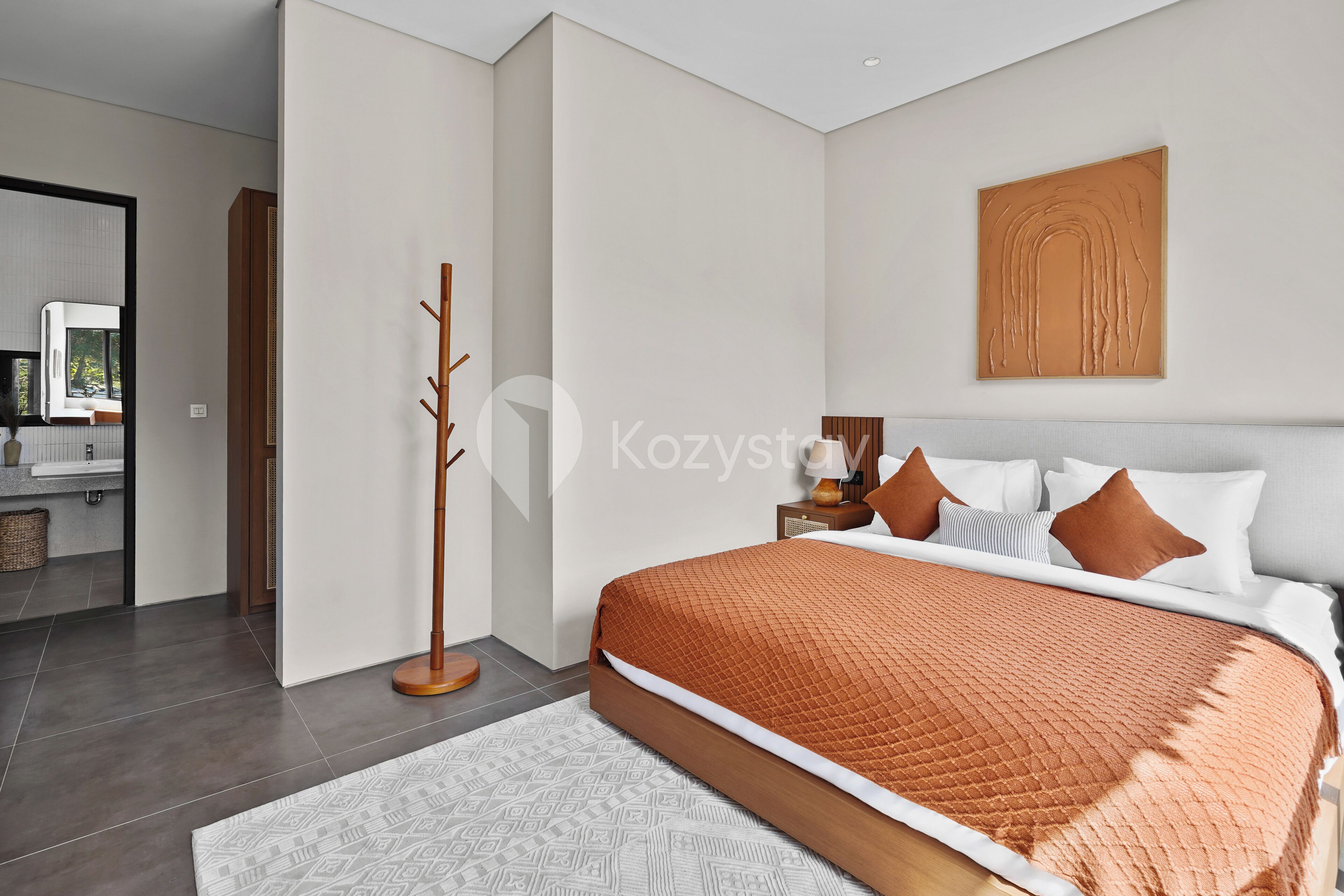 Un dormitorio moderno con una cama grande, una lámpara de pie de madera y una obra de arte colgada en la pared.