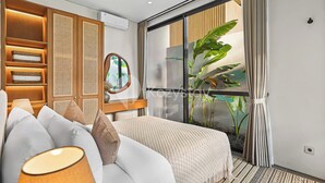 Een moderne hotelkamer met een groot bed, een nachtkastje met lamp, een houten garderobe, een groot raam met uitzicht op groen, en een wandairconditioner.