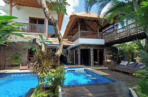 A two-story house with a swimming pool, wooden deck, and outdoor furniture. - 5 Bedroom luxury villa in the heart of Seminyak (Bali)