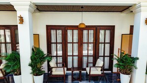 A poolside area with two chairs and a table, surrounded by potted plants.