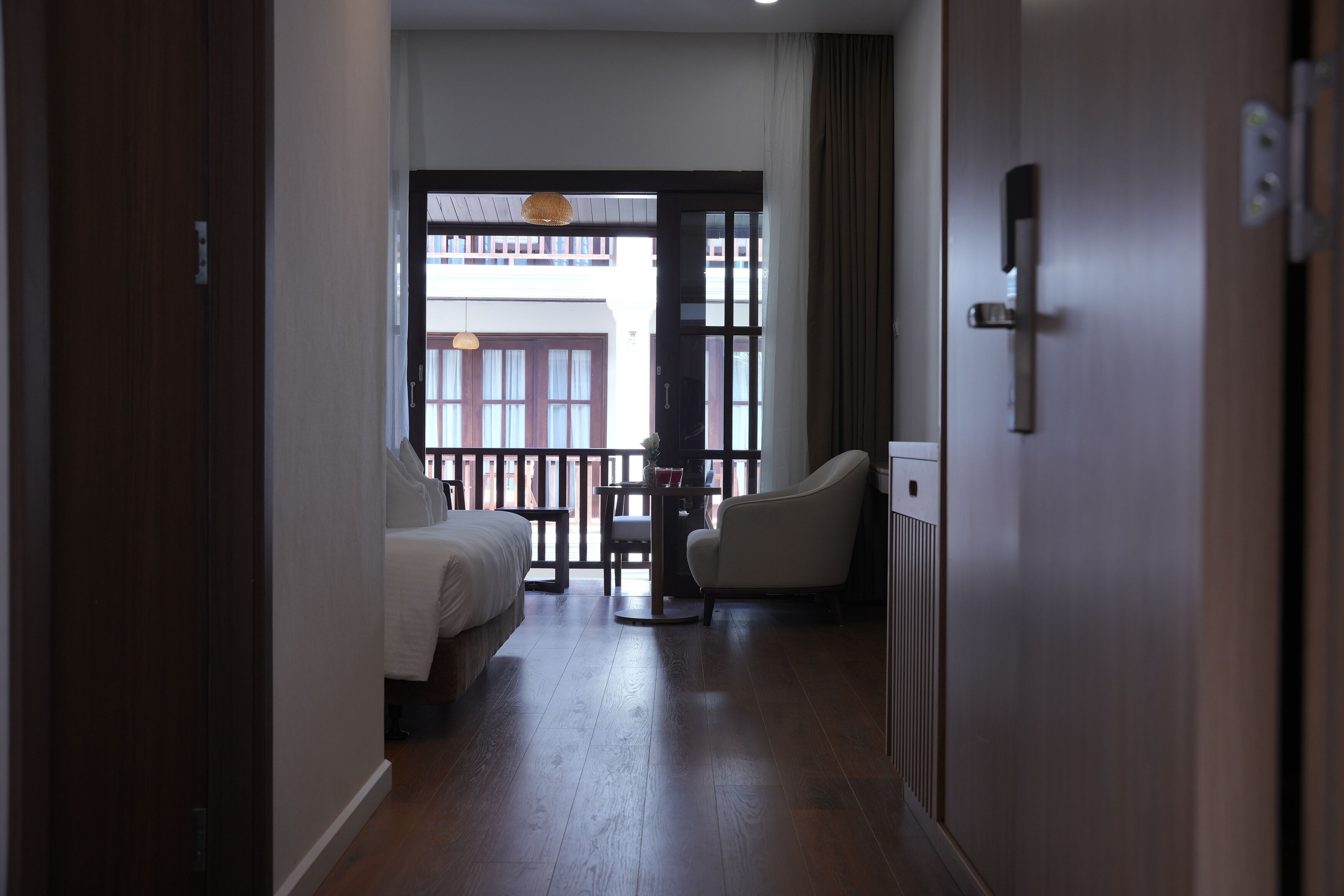 Une chambre d’hôtel avec un lit, une chaise, une petite table et une vue sur le balcon extérieur.